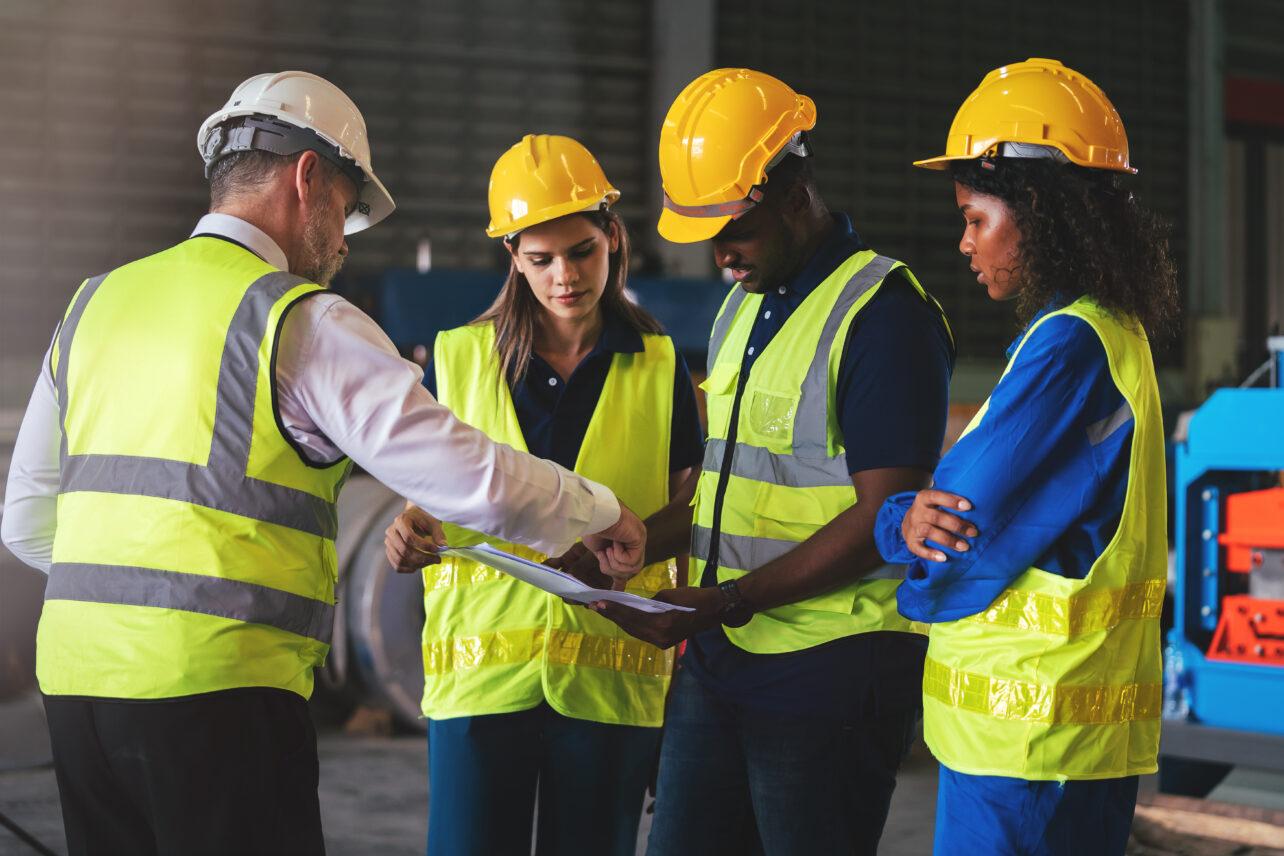 Group of workers in safety gear reviewing a document together