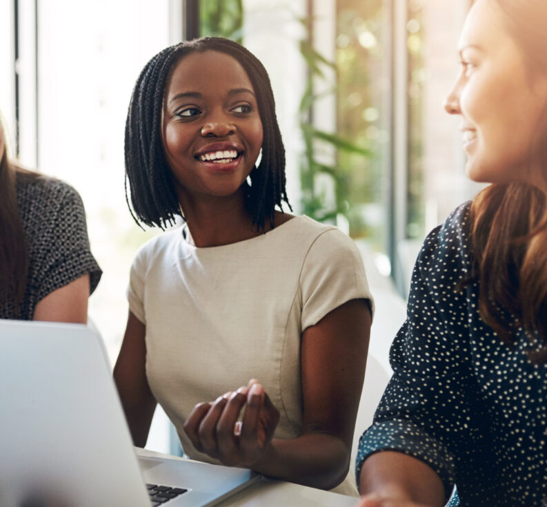 Three professional women meeting around a laptop