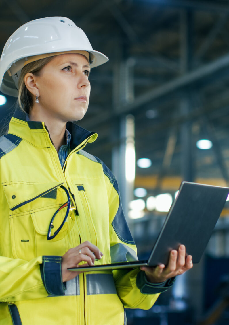 Employée du secteur de l'électricité portant un casque et étudiant un ordinateur portable