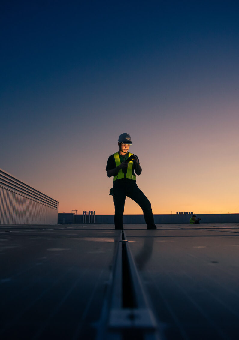 Un ingénieur vérifiant l’installation d’une cellule solaire sur le toit d’une usine le matin.