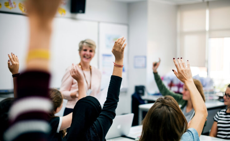 Students with their hands up responding to their teacher