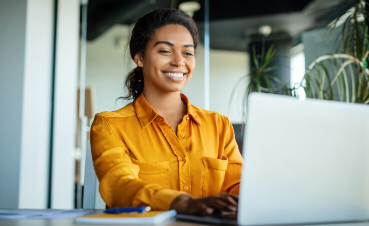 A black businesswoman using a laptop typing at a desk