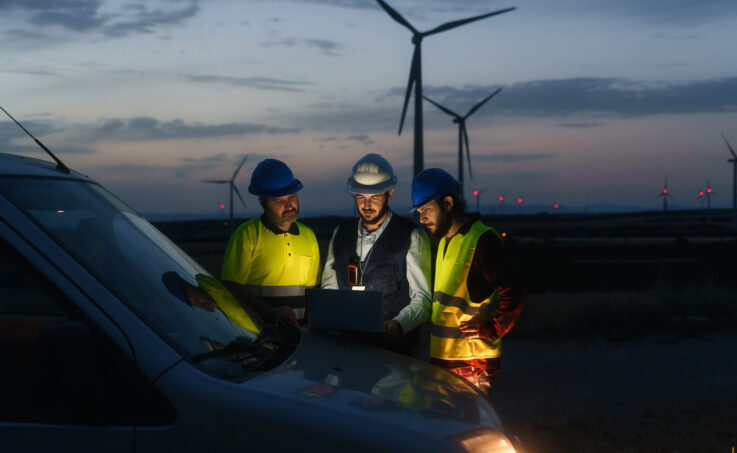 Technicians working at a wind turbine electricity facility at night