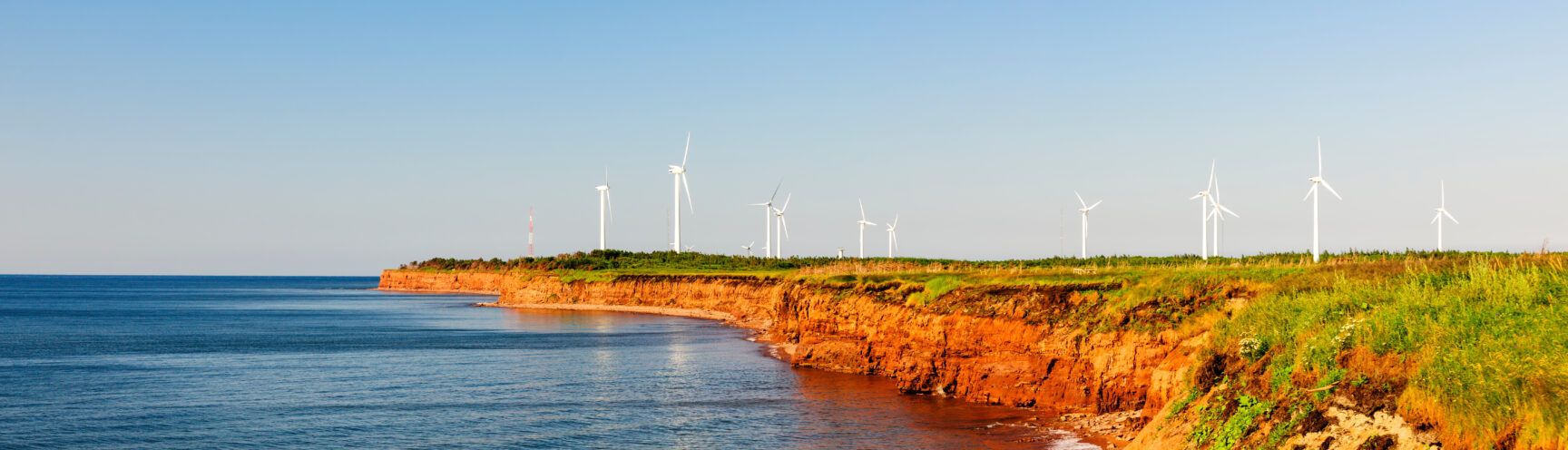 PEI's red sandy coastline with wind power generators in the background.