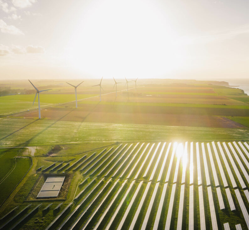 Wind turbines and solar panels farm in a field. 