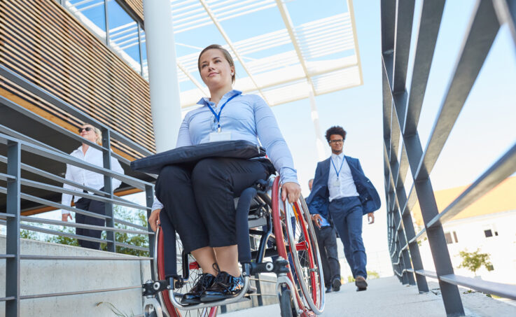 Disabled woman in a wheelchair on a ramp to the barrier-free business office