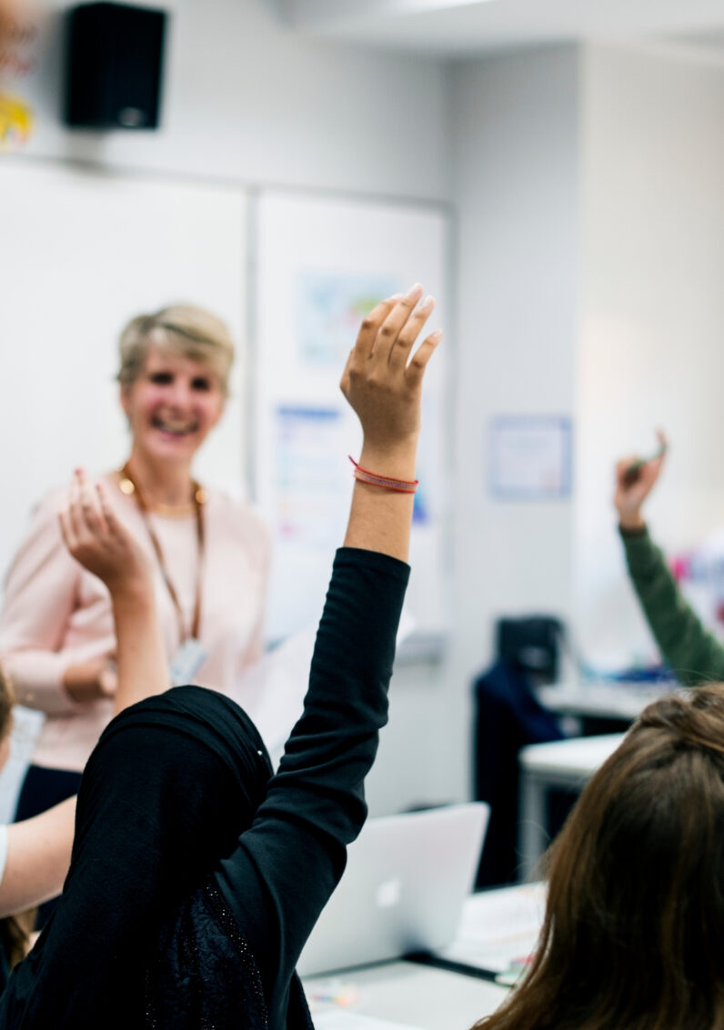 Étudiant·e·s avec les mains en l’air répondant à leur professeure
