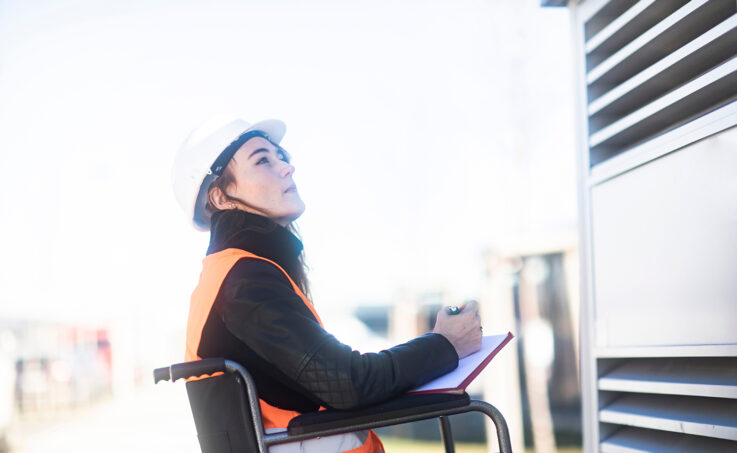 An electricity industry professional who is in a wheelchair doing an inspection