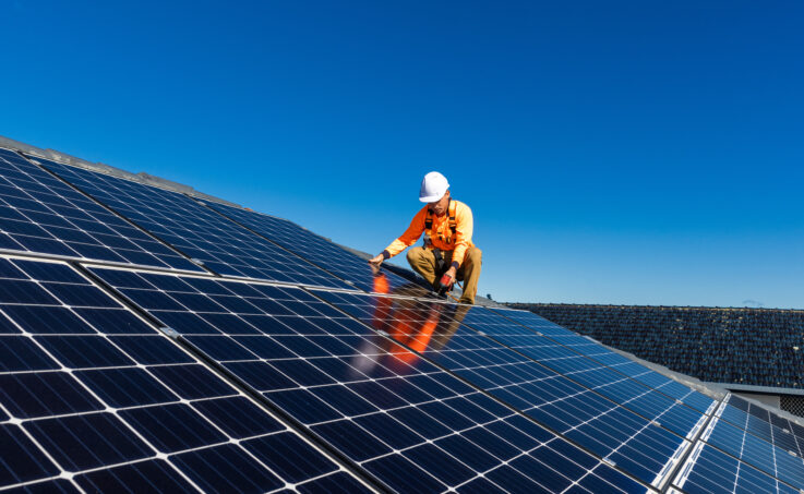 Worker placing solar panels on a roof