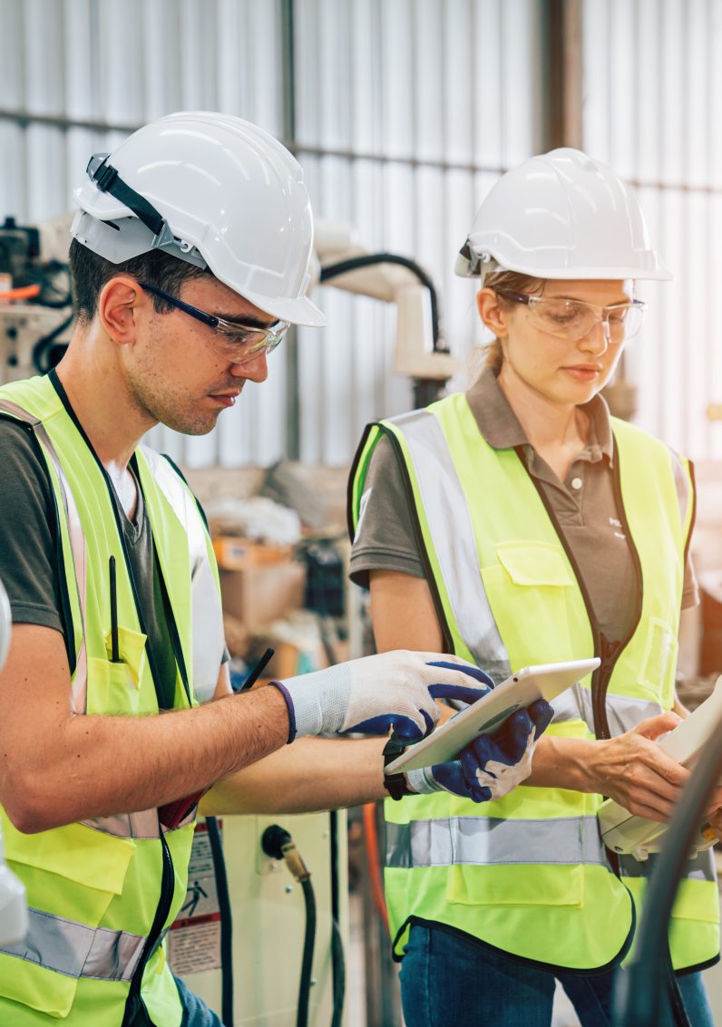 Team of engineers or worker is controlling robot arm machine welding steel, worker using forcing welding with a control screen which is used for precision welding control.
