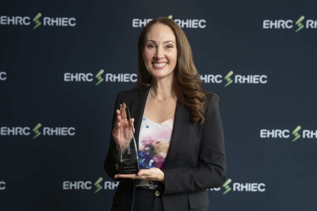 Award recipient smiles and poses with their award