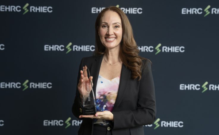 Award recipient smiles and poses with their award