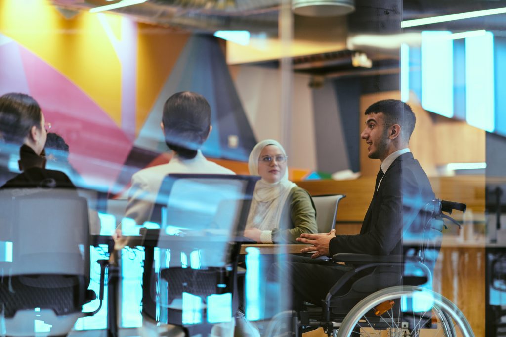 Group of colleagues having a meeting in a modern office, one participant using a wheelchair.