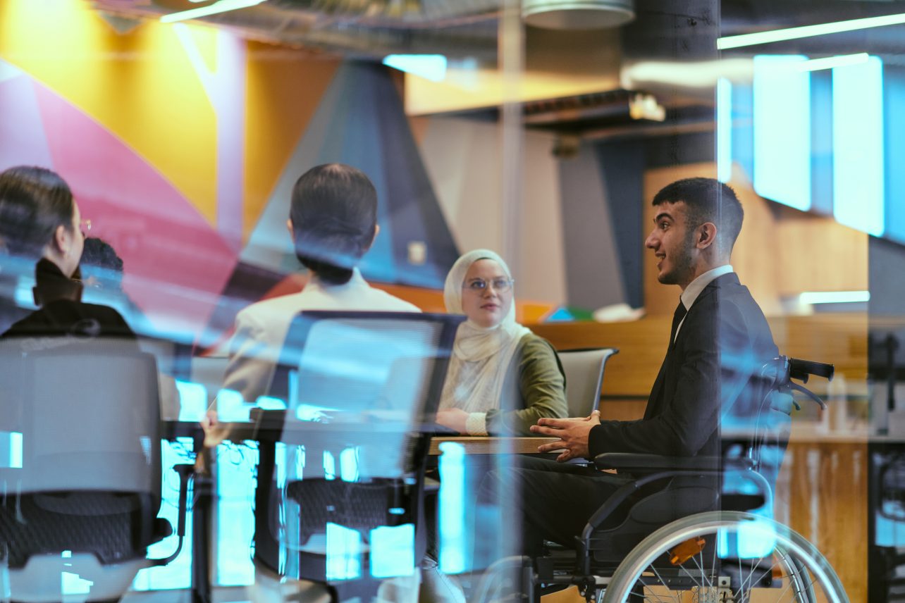 Group of colleagues having a meeting in a modern office, one participant using a wheelchair.