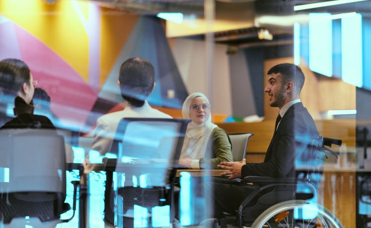 Group of colleagues having a meeting in a modern office, one participant using a wheelchair.