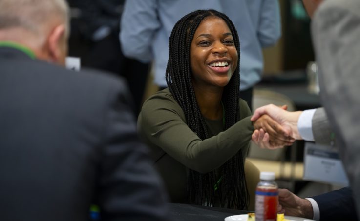 Attendee smiles while shaking hands with someone